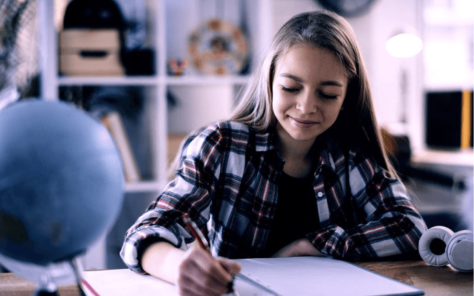 Girl in a checkered shirt writing in a notebook