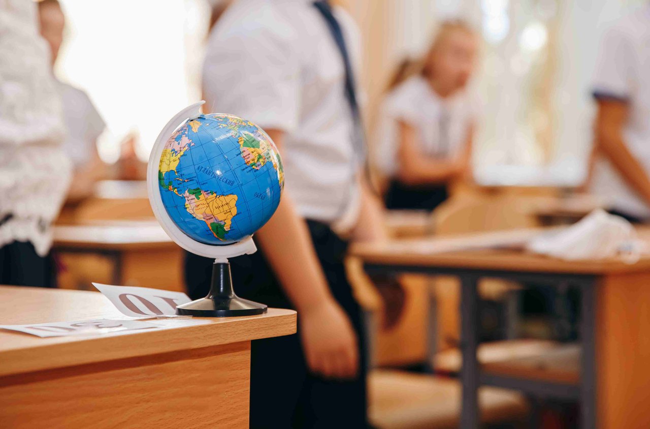Image of a classroom with a globe on the edge of a school desk