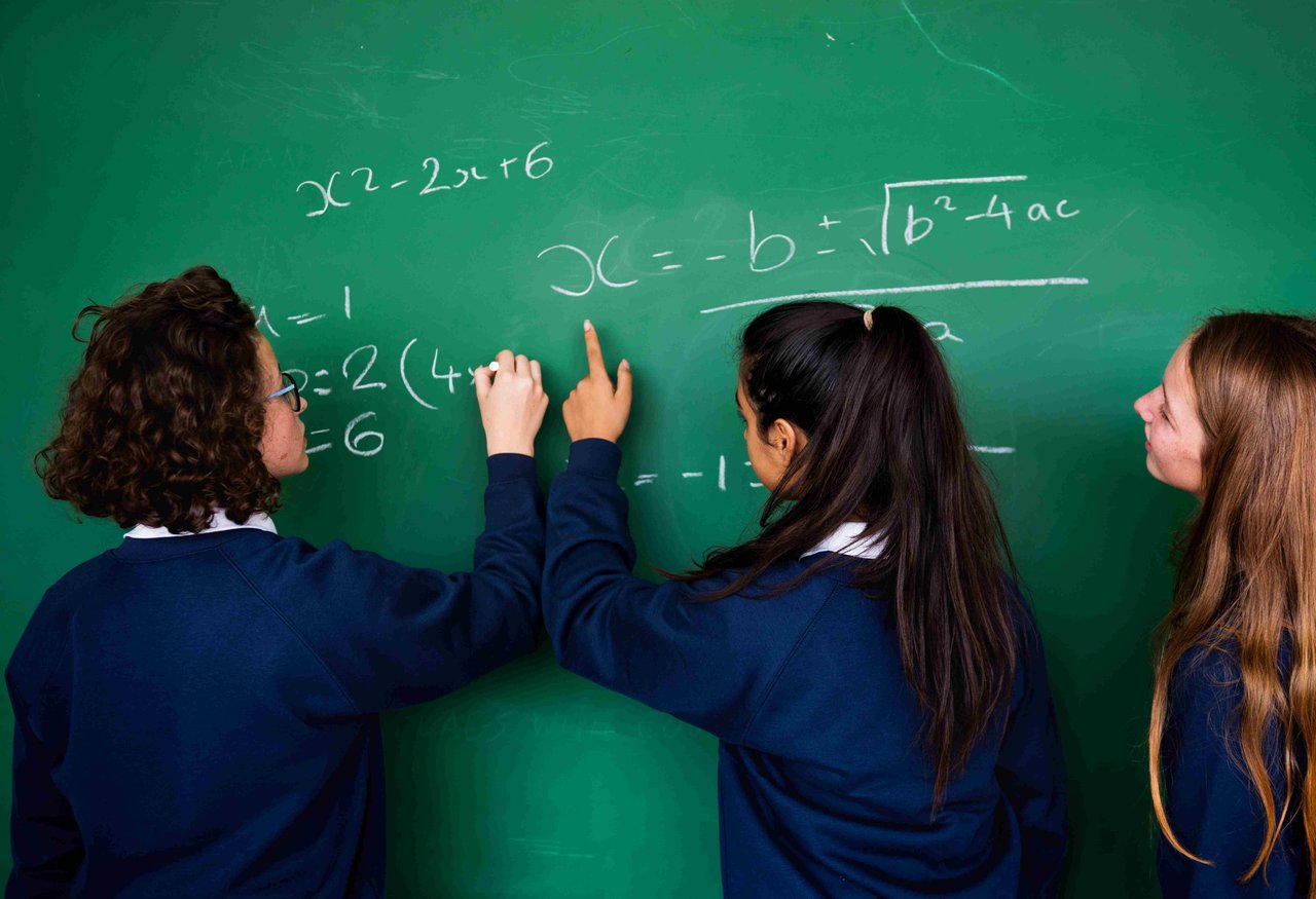 Three female students writing on a chalkboard