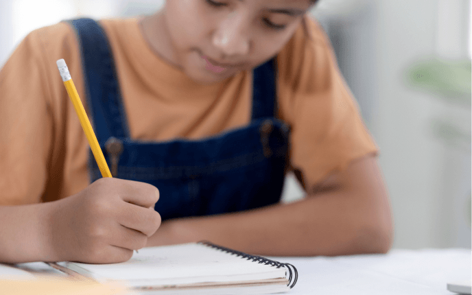 Young girl in dungarees writing in a notepad