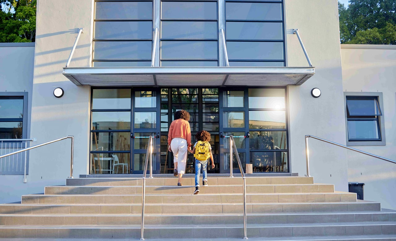 A mother and child walking into a secondary school building