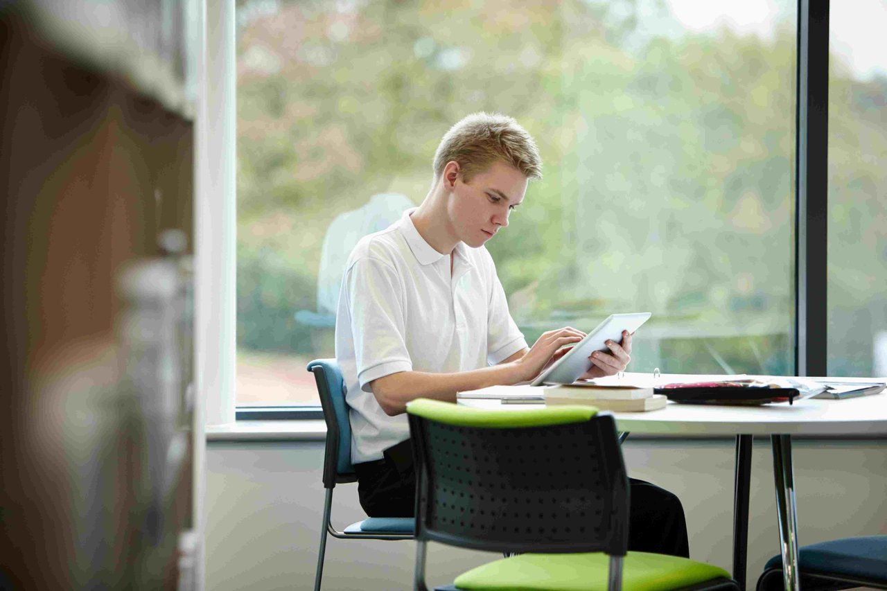 Teenage boy looking at a tablet screen in a school library
