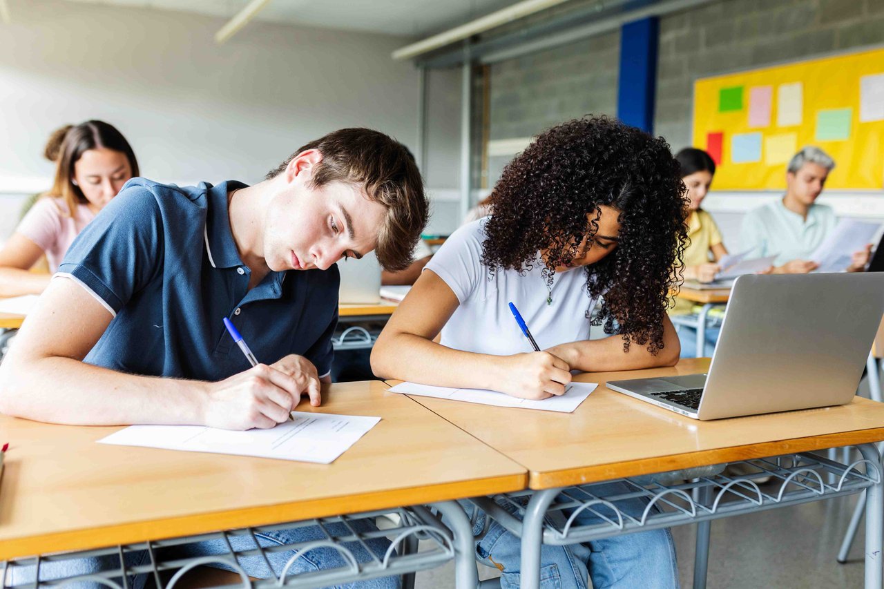 A male and female student sat in a classroom completing a GCSE past paper.