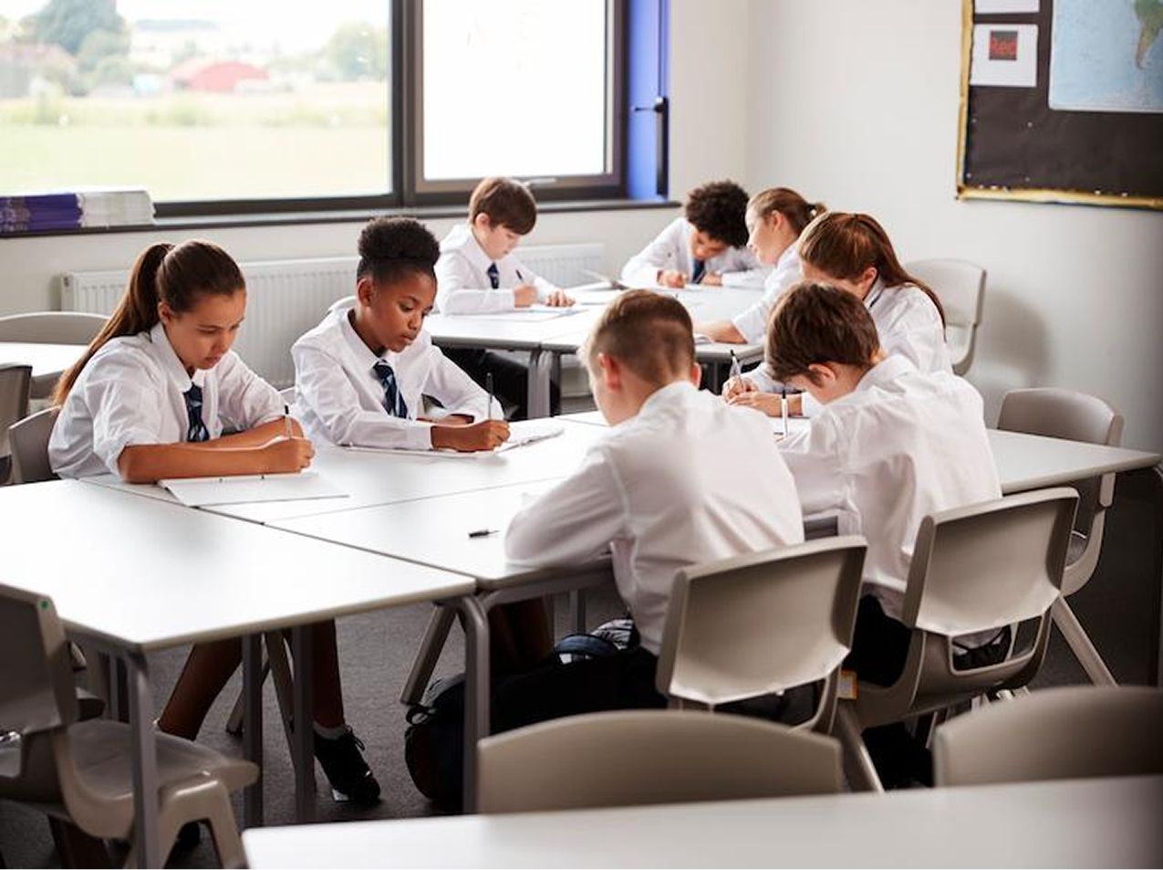 A group of students in uniform, sat working around a table
