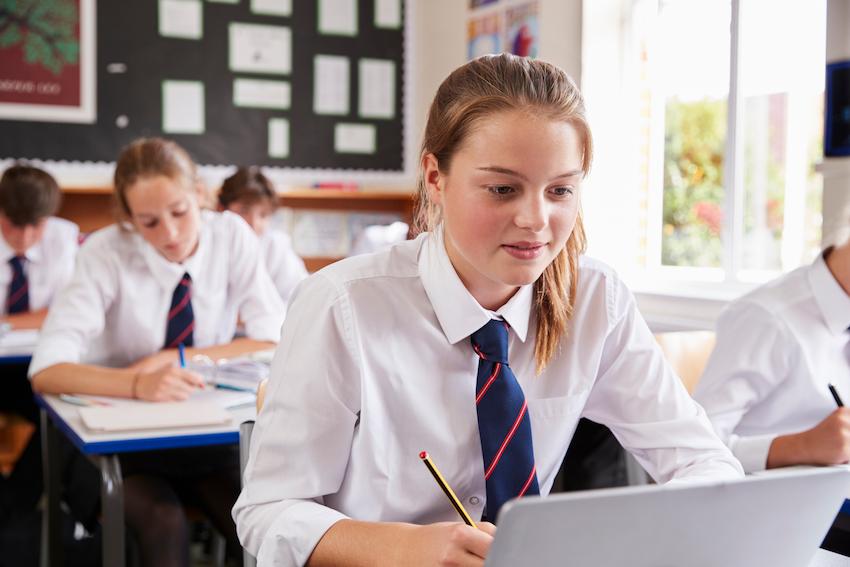 Brunette girl in formal school uniform working in a classroom