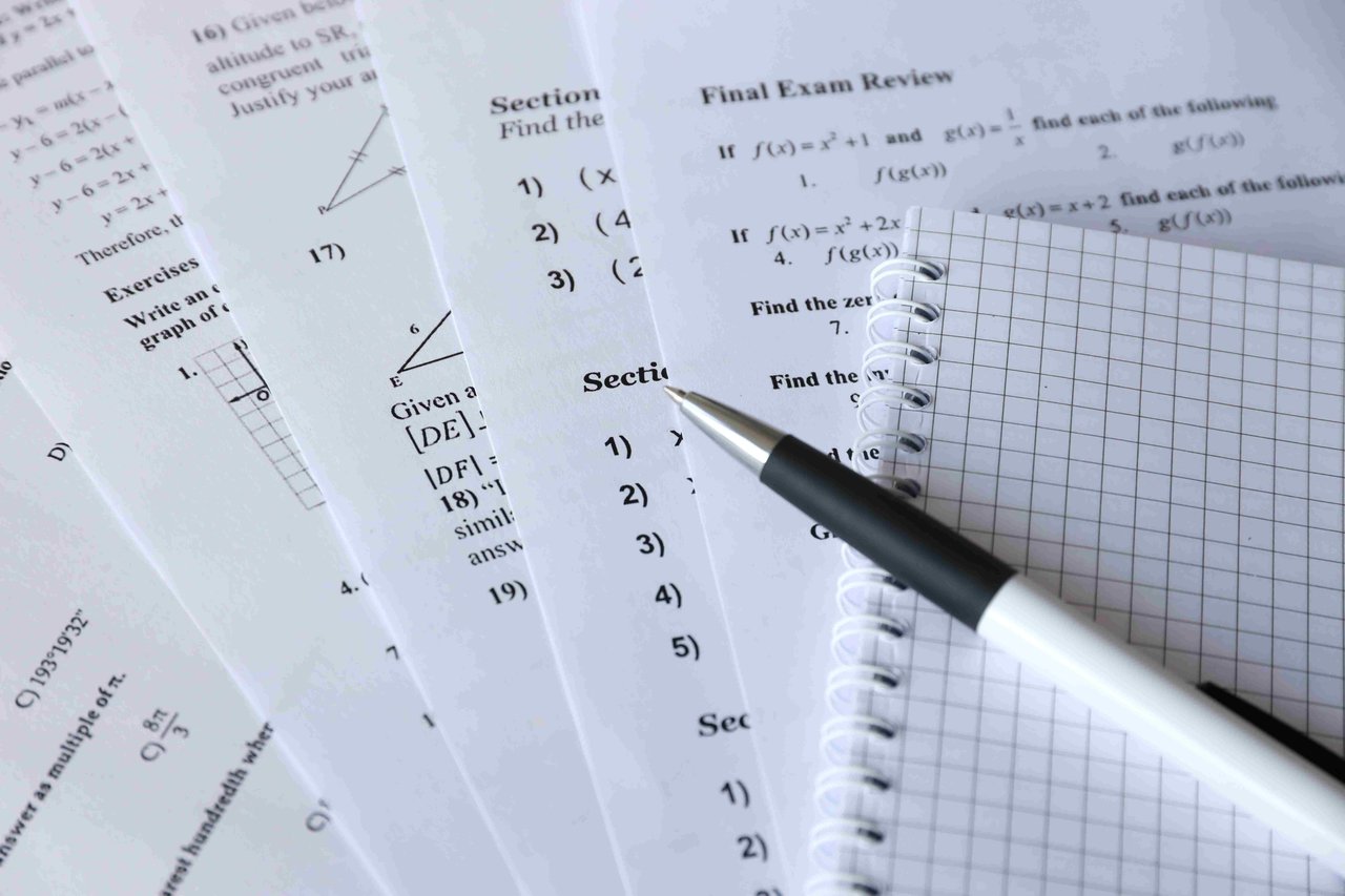 A selection of GCSE exam papers, with a pen and paper