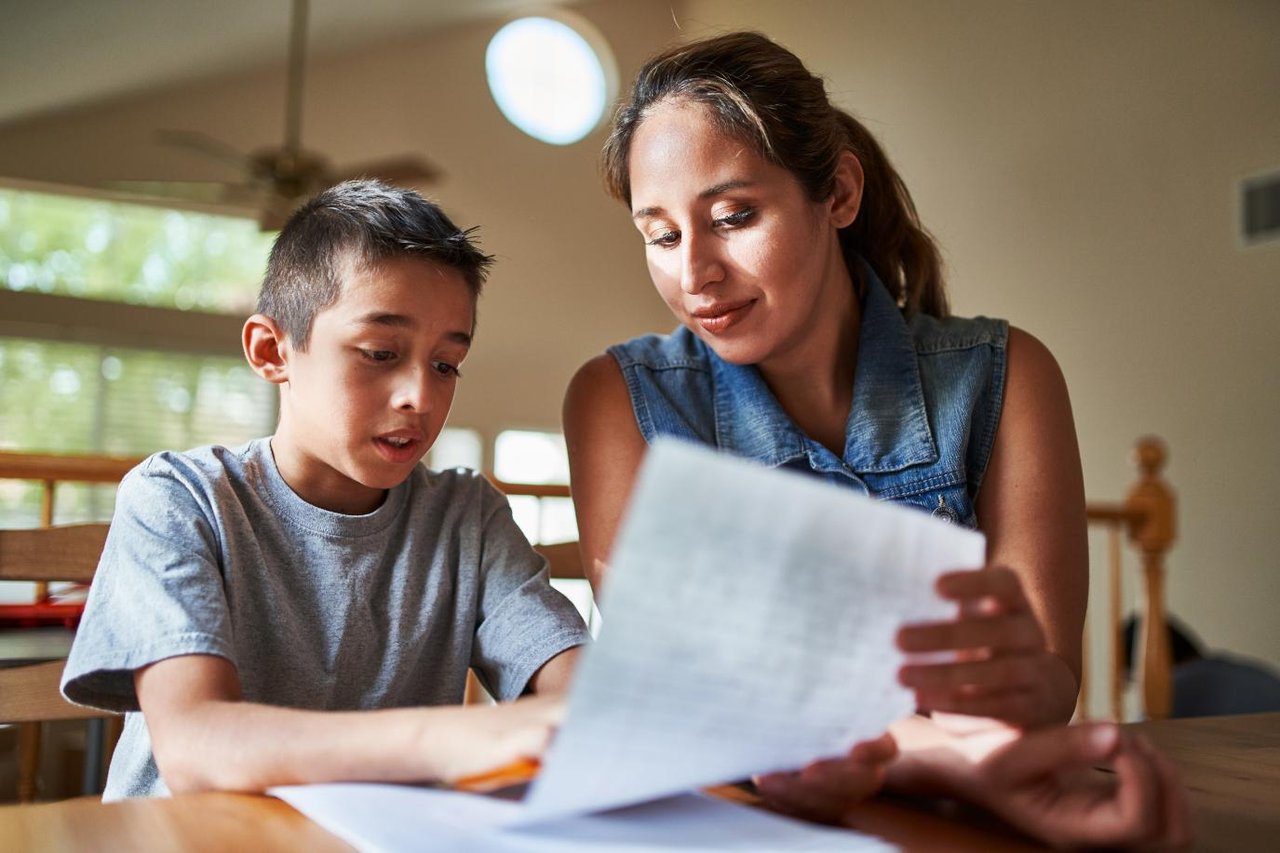 Mother and son sitting at a table and looking at a sheet of paper togeth