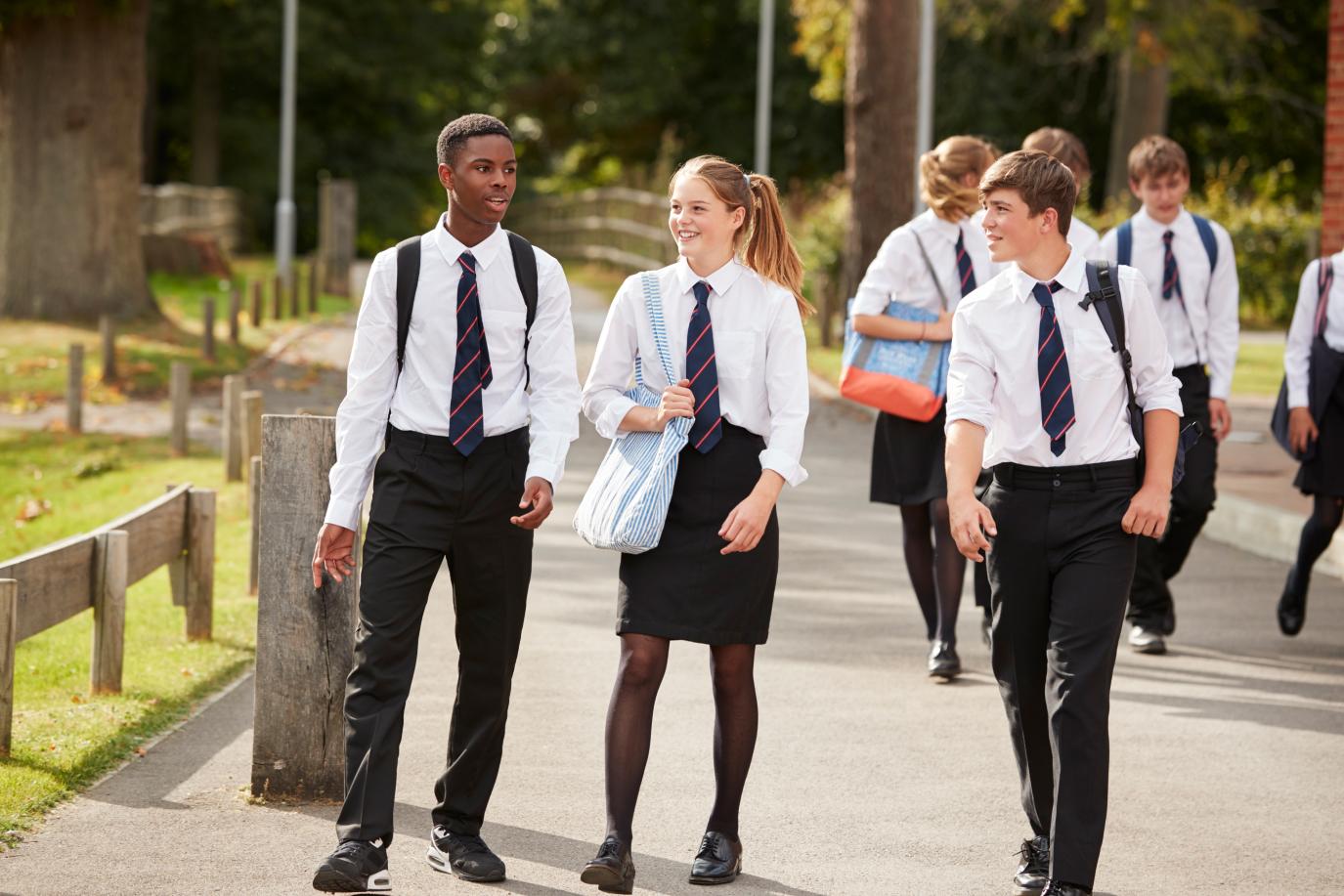 Group of teenagers in school uniform walking down a path together