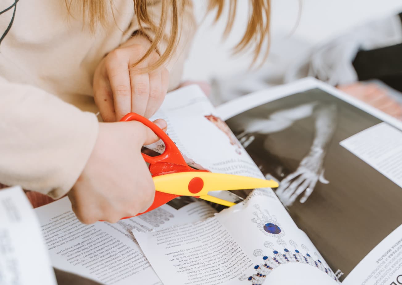 A child cutting out words from a magazine